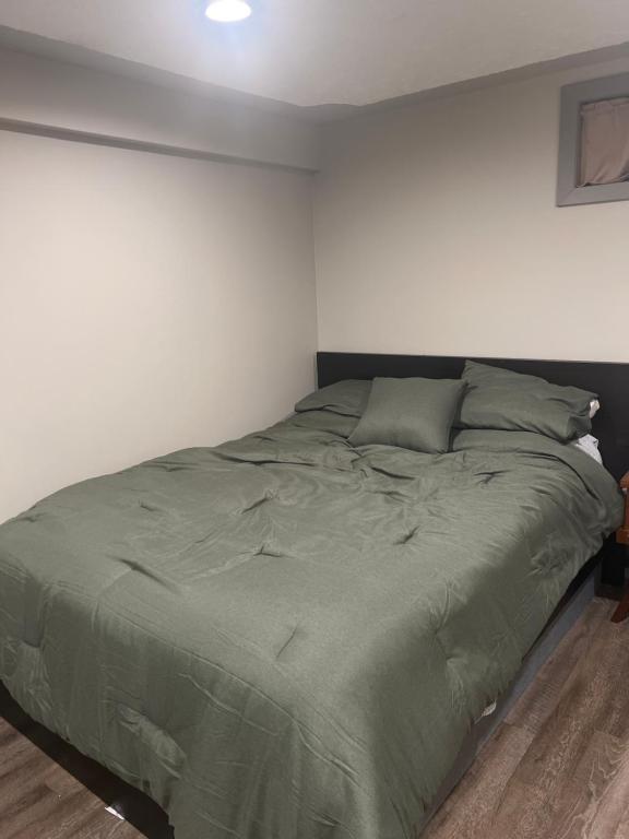 Cama en habitación con pared blanca en Spacious Room & Living Area in NW! en Calgary