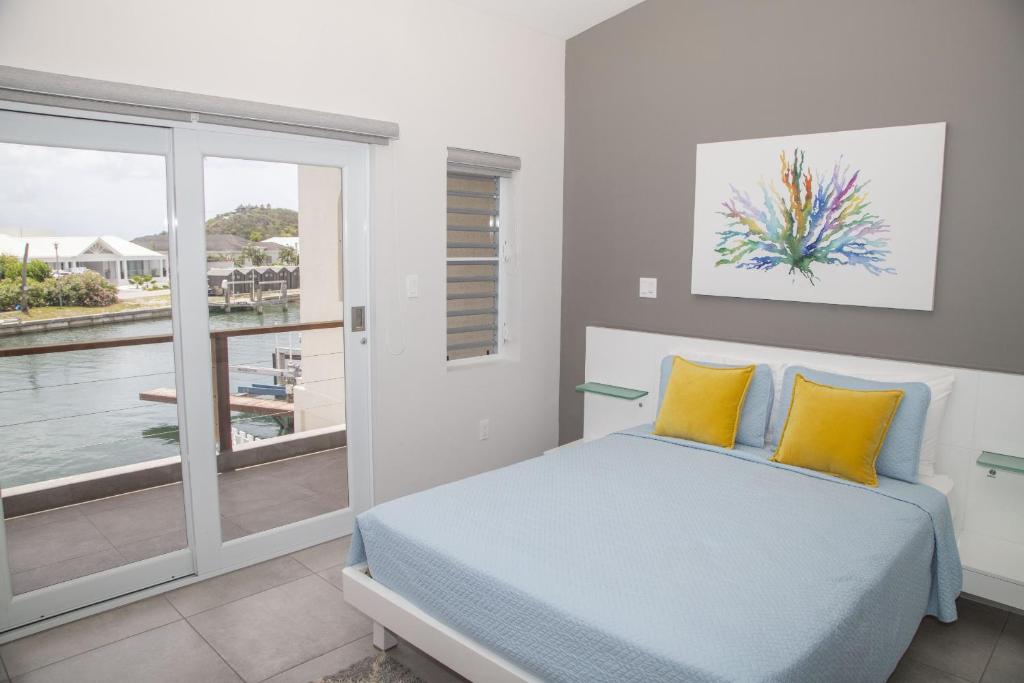 a bedroom with a bed with yellow pillows and a balcony at 246D South Finger in Jolly Harbour