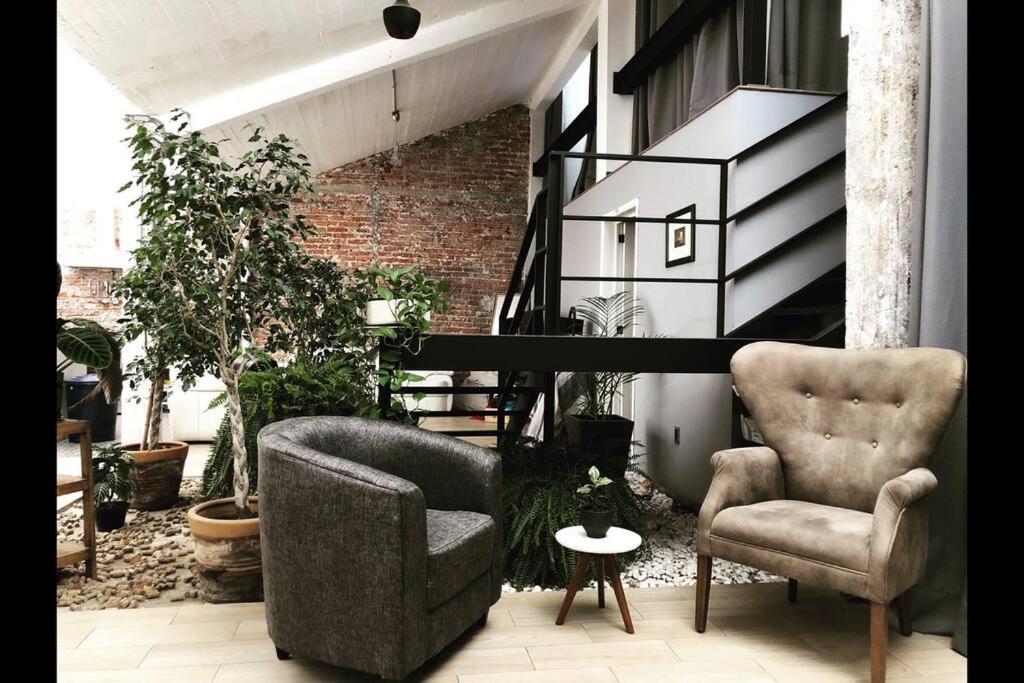 ein Wohnzimmer mit 2 Stühlen und einer Treppe in der Unterkunft Loft Condesa in Mexiko-Stadt