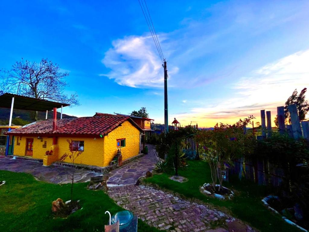 una pequeña casa amarilla en medio de un patio en Finca La Aurora Hospedaje Rural de Montaña, en Tibasosa
