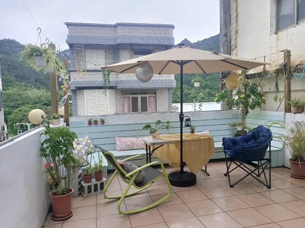 un patio con mesa, sombrilla y sillas en 七十腳落背包客棧 en Green Island