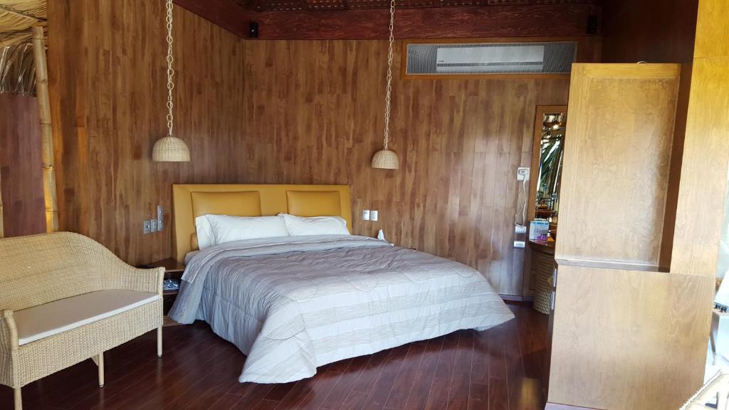 Thai Lagoon Select Motel في Laurel de Lagunillas: غرفة نوم بسرير وجدار خشبي