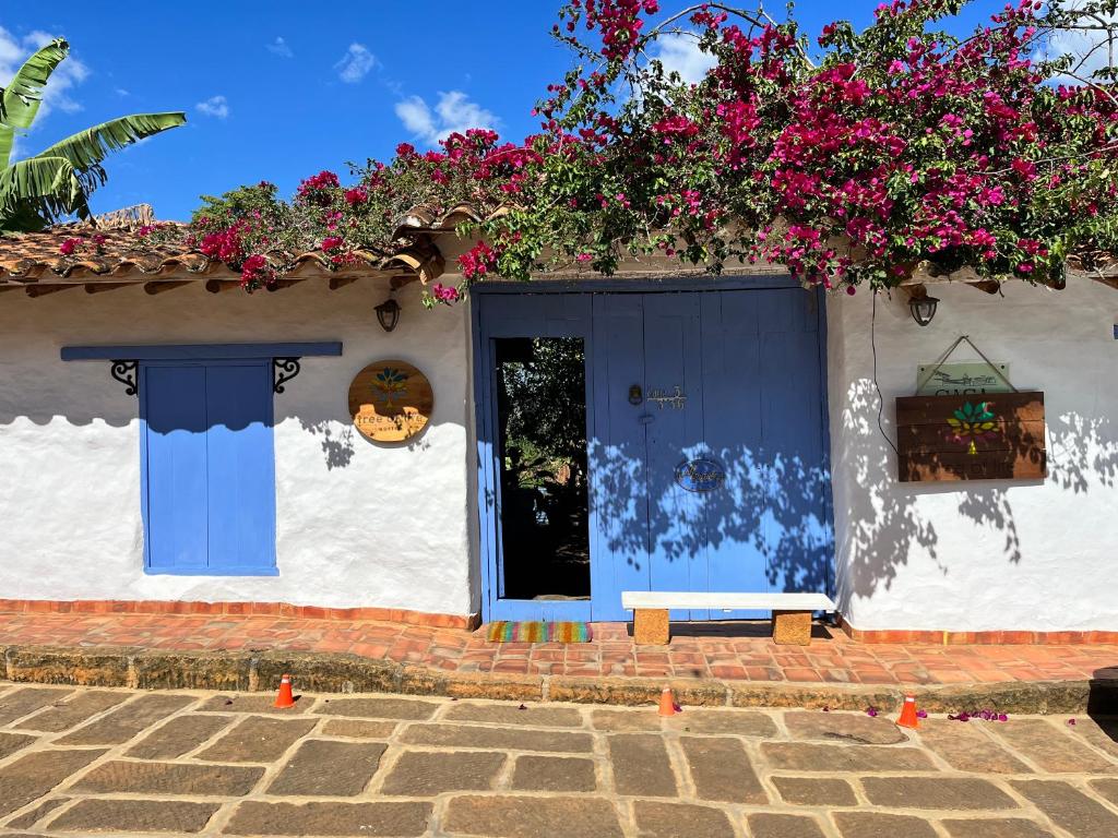 une maison avec une porte bleue et quelques fleurs dans l'établissement Tree of Life - Hostel, à Barichara