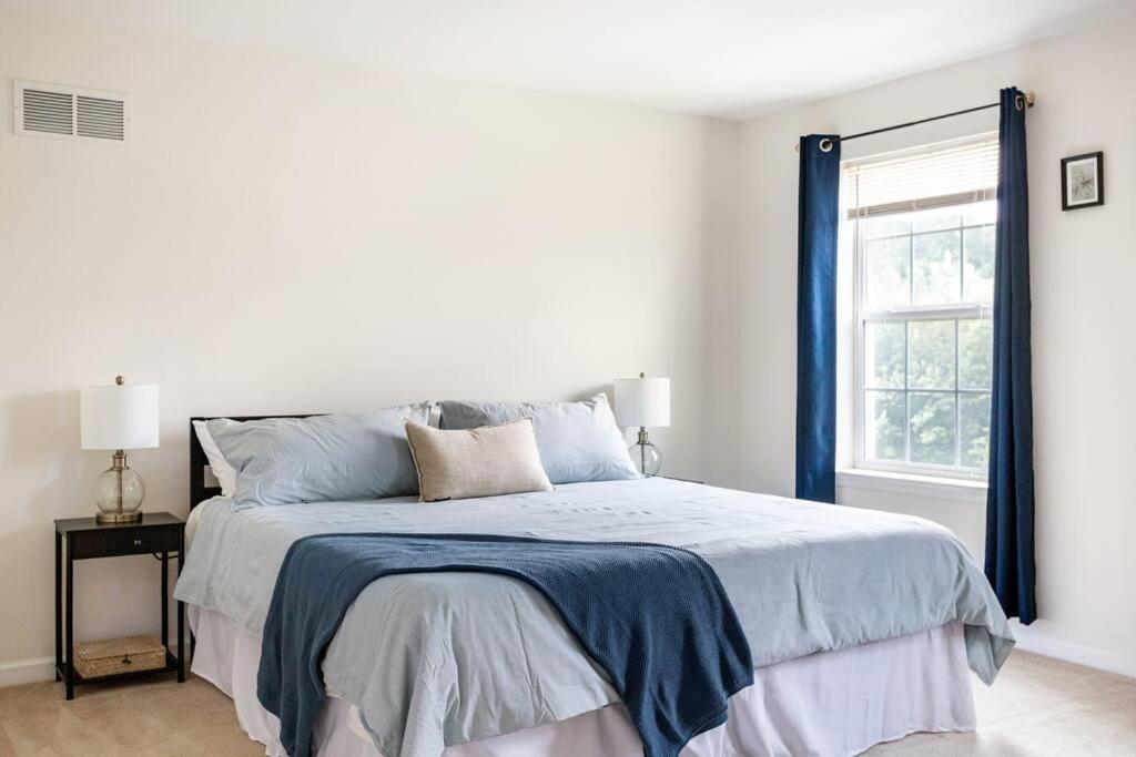 - une chambre blanche avec un lit et une couverture bleue dans l'établissement Spacious and Modern Townhome minutes from UDel, à Newark
