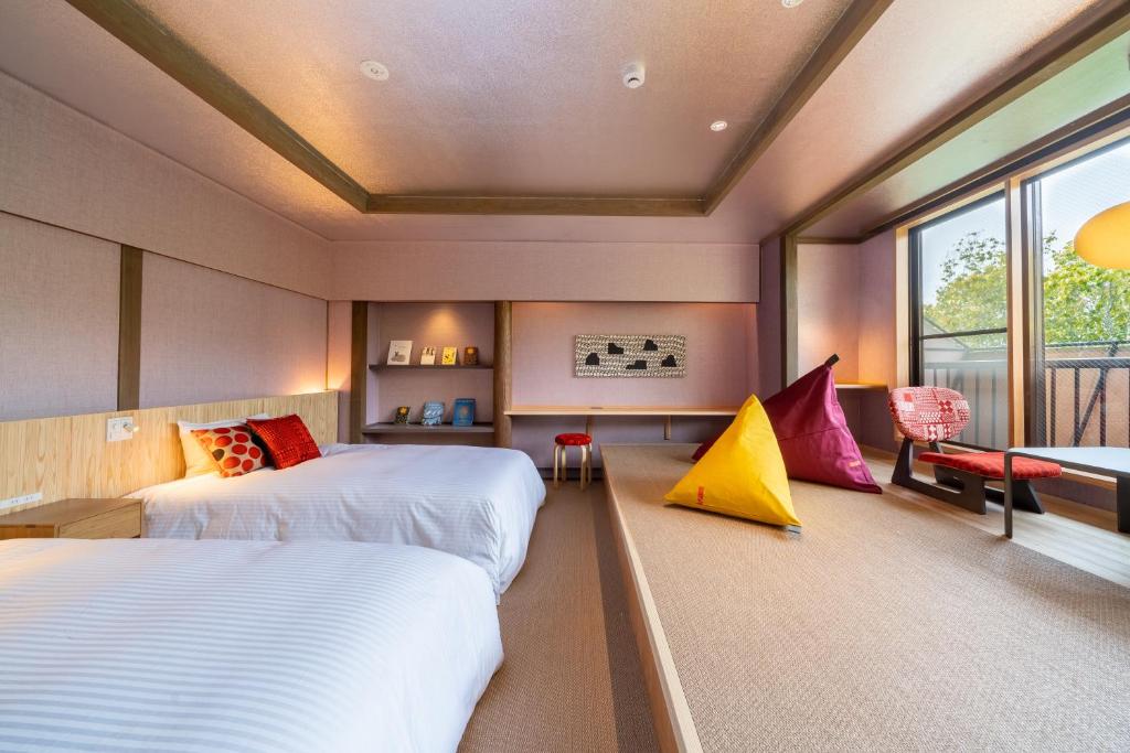 1 dormitorio con 2 camas y ventana en Enokiya Ryokan, en Yufu
