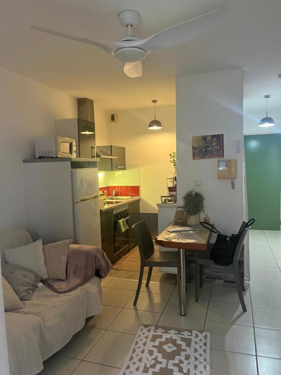 een woonkamer en een keuken met een bank en een tafel bij P’tit Cosy St Denis - centre in Saint-Denis