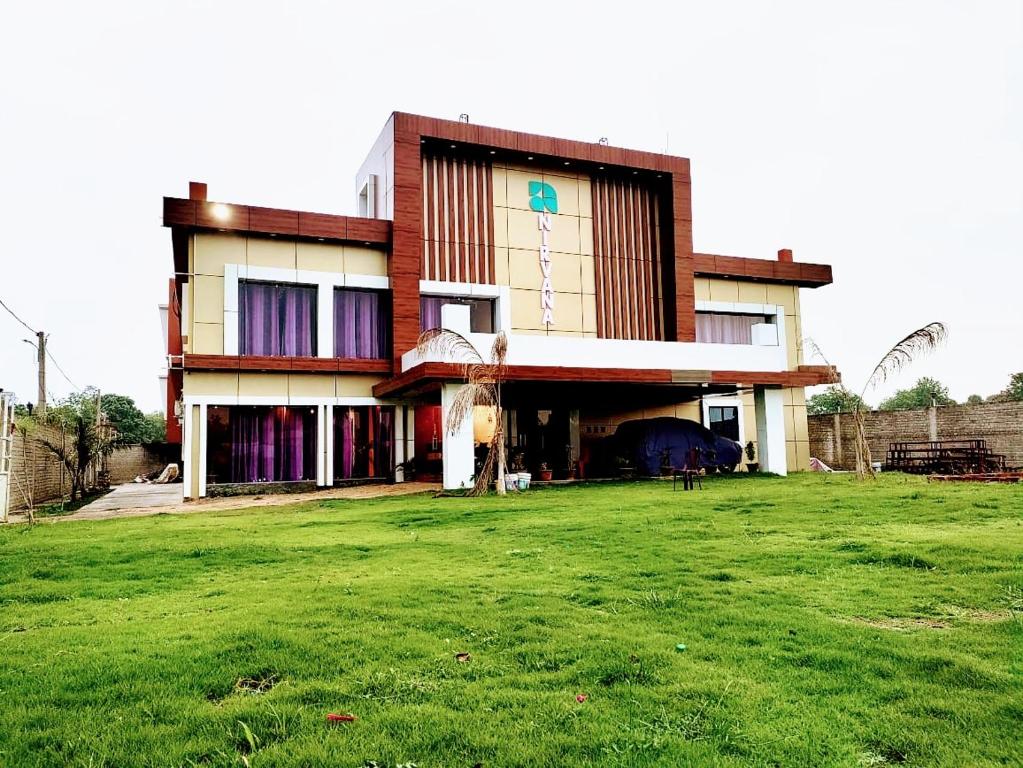 a house with a green field in front of it at The Nirvana Resort in Chatra