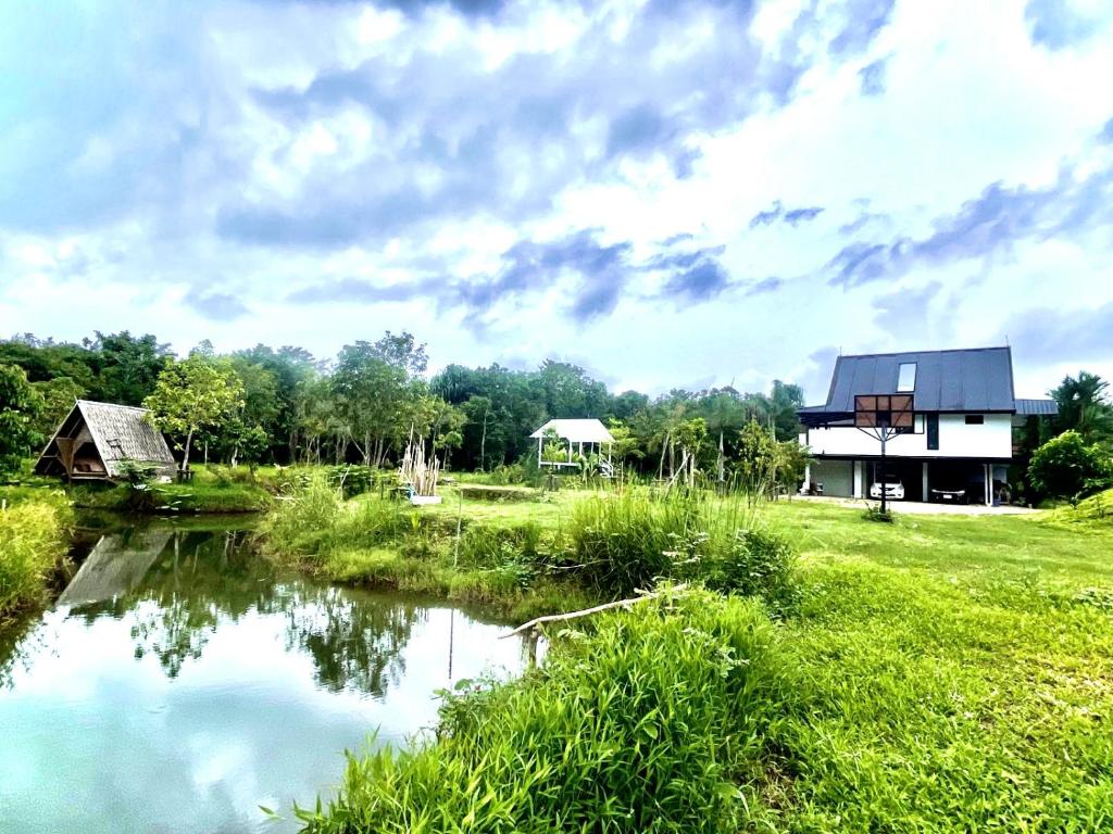 une maison à côté d'une rivière dans un champ dans l'établissement Quiet LakeHouse Appartement on Memory Beach road, à Khao Lak