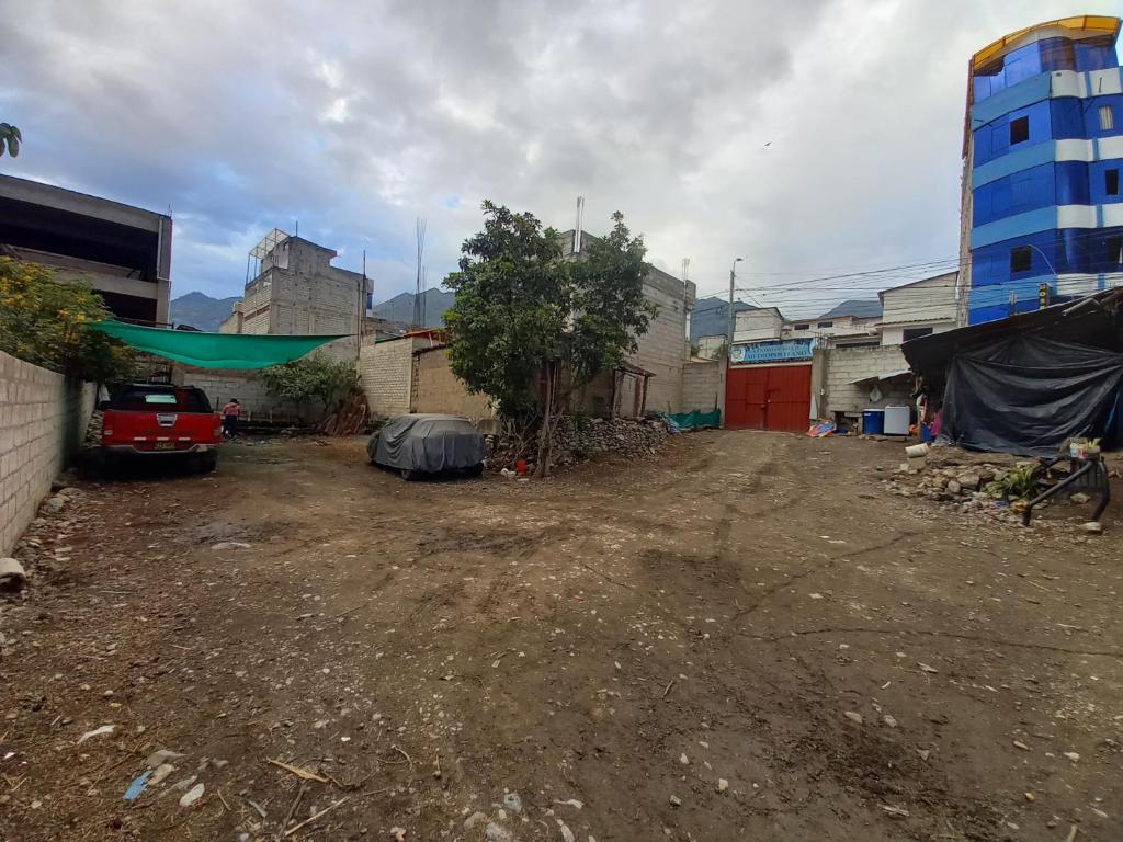 un patio de tierra con un coche estacionado frente a los edificios en Hostal Garcilaso - Garaje Amplio en Abancay