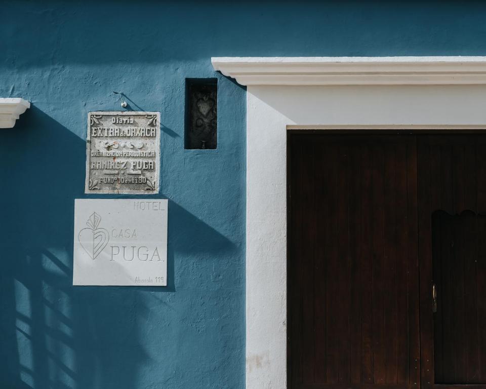 een blauwe muur met een deur en een bord erop bij Hotel Casa Puga in Oaxaca City