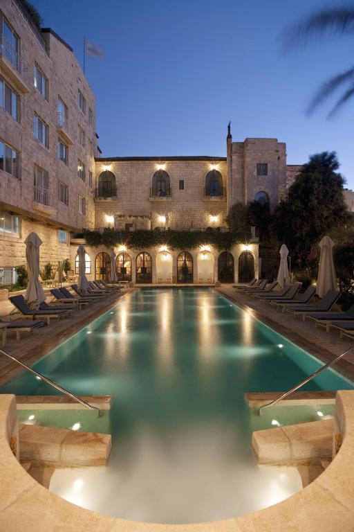 a swimming pool with chairs and a building at The American Colony Hotel - Small Luxury Hotels of the World in Jerusalem