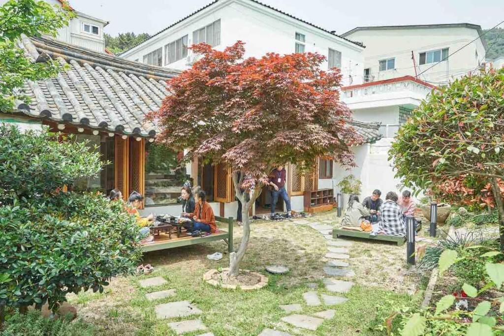 grupa ludzi siedzących na podwórku domu w obiekcie Inner-Stay w mieście Tongyeong