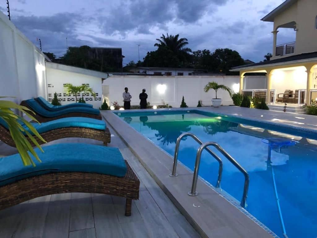 a swimming pool with chairs next to a house at villa piscine orchidée in Pointe-Noire