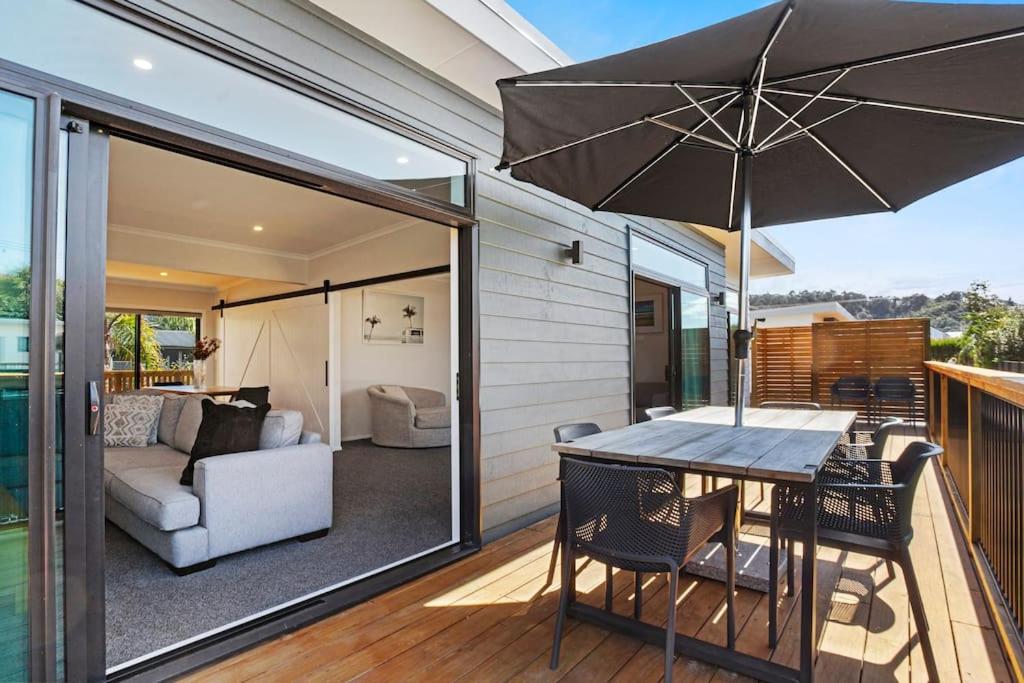 a patio with a table and chairs and an umbrella at Leisure on Leo in Waihi Beach