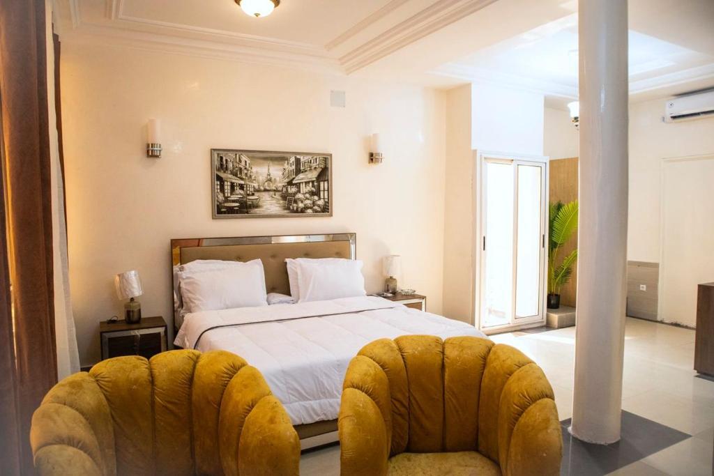 1 dormitorio con 1 cama y 2 sillas en residence queen house en Brazzaville