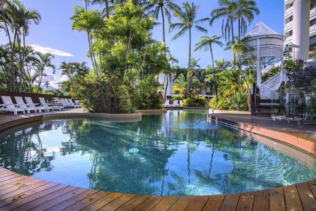 a swimming pool in a resort with chairs and palm trees at 'Luxury Waterfront' Spectacular Oasis in the City in Cairns