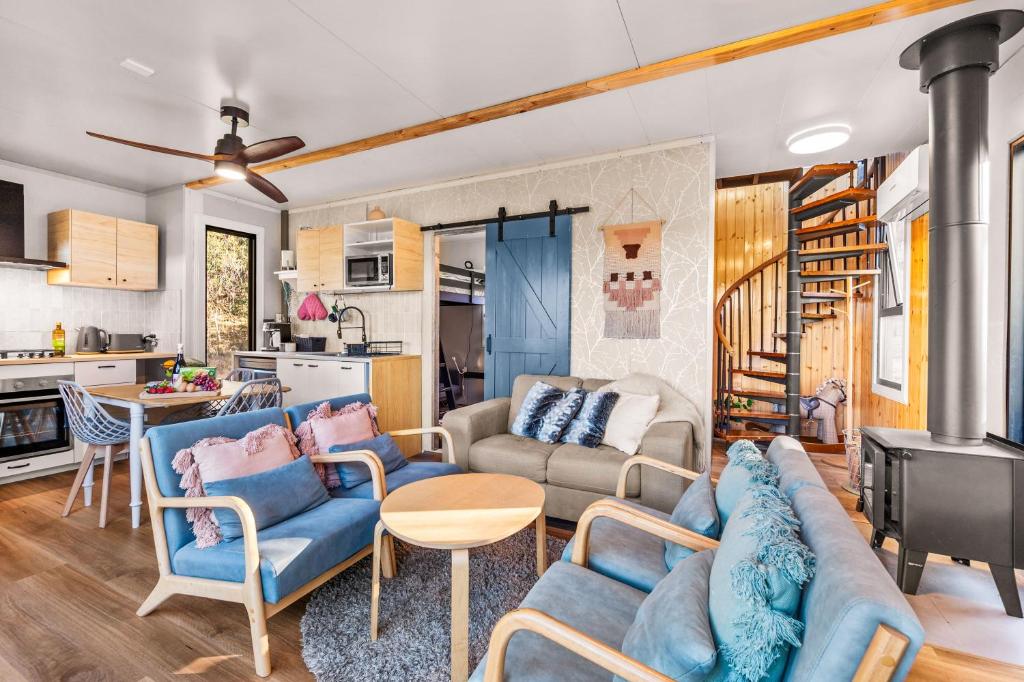 a living room with blue furniture and a kitchen at Delightful Container House with Views in Hartley
