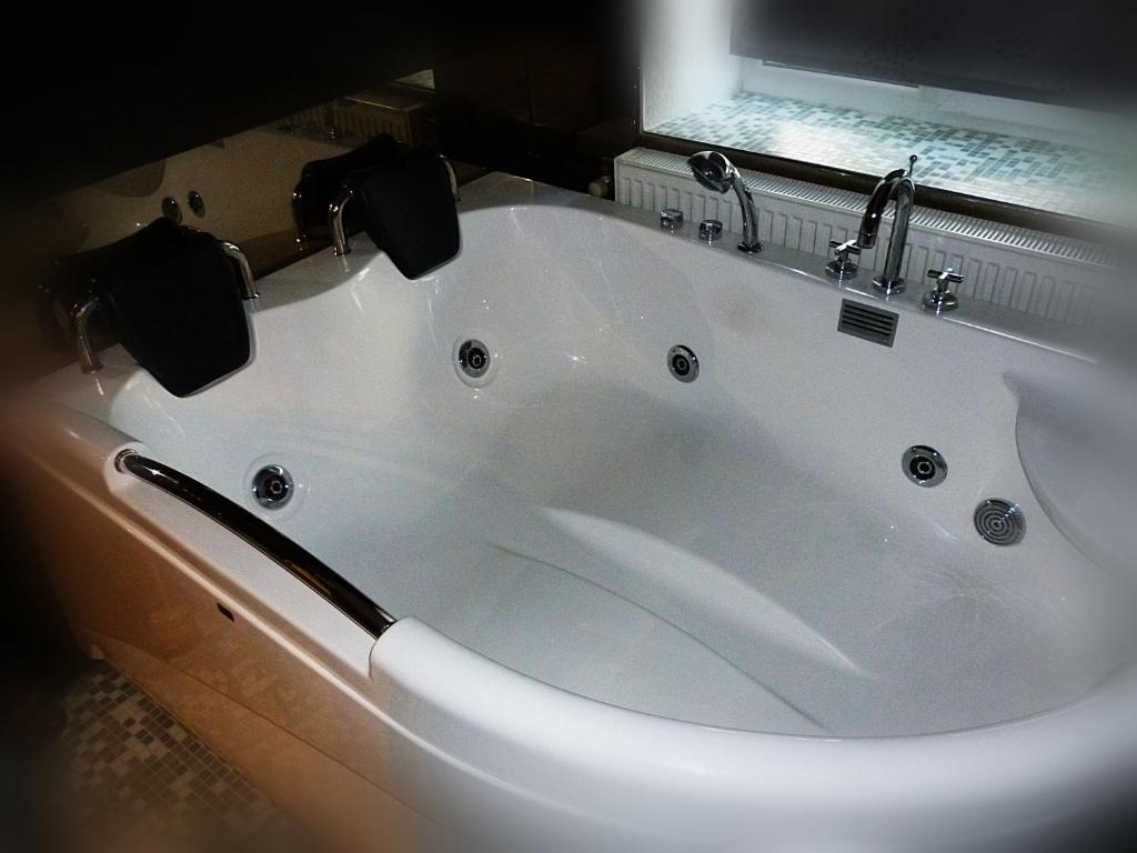 a white bath tub with two faucets in a bathroom at Ditton apartment city center in Daugavpils
