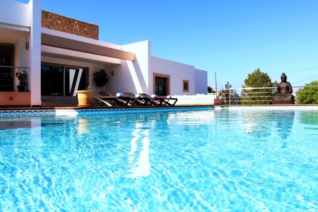 - une piscine avec des chaises en face d'une maison dans l'établissement Villa Bellissima, à Bahía de Sant Antoni