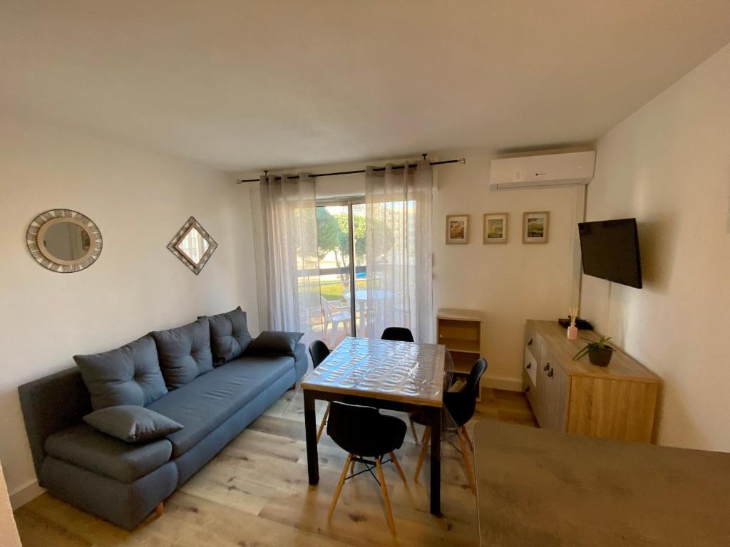 un salon avec un canapé bleu et une table dans l'établissement Studio en bord de marina, à Canet