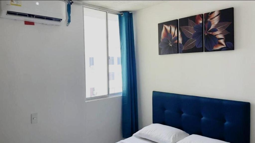 um quarto com uma cabeceira azul e uma janela em Apartamento Amoblado Cartagena em Cartagena das Índias