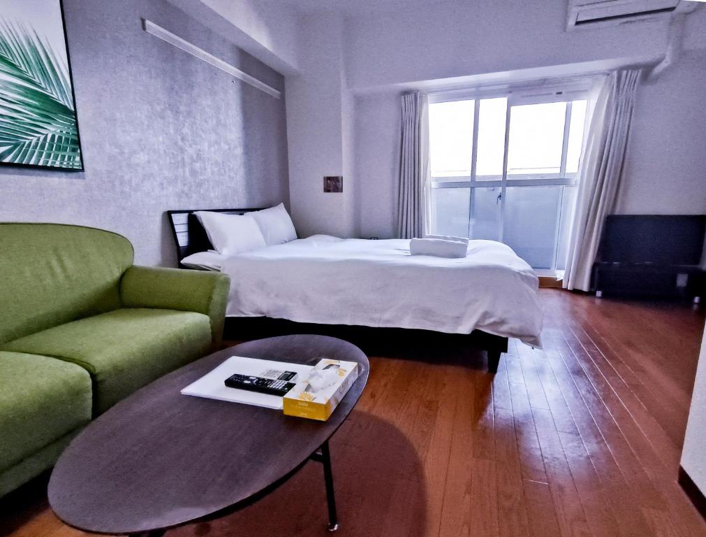 a hotel room with a bed and a couch and a table at Ostay Kitahama Hotel Apartment in Osaka