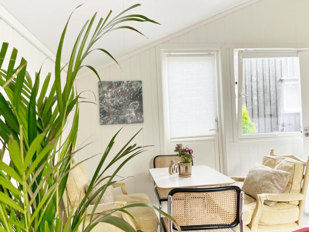 a living room with a table and chairs and a plant at Brightside Apartment in Kristiansand