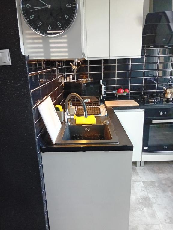 a kitchen with a sink and a clock on the wall at Mieszkanie na doby w Kutnie centrum ulPodrzeczna in Kutno