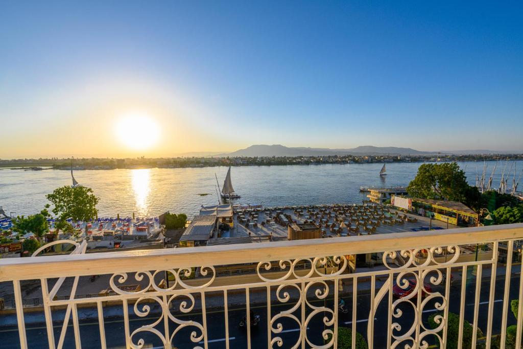 a large boat docked on a river with the sunset at Rhapsody of Luxor in Luxor