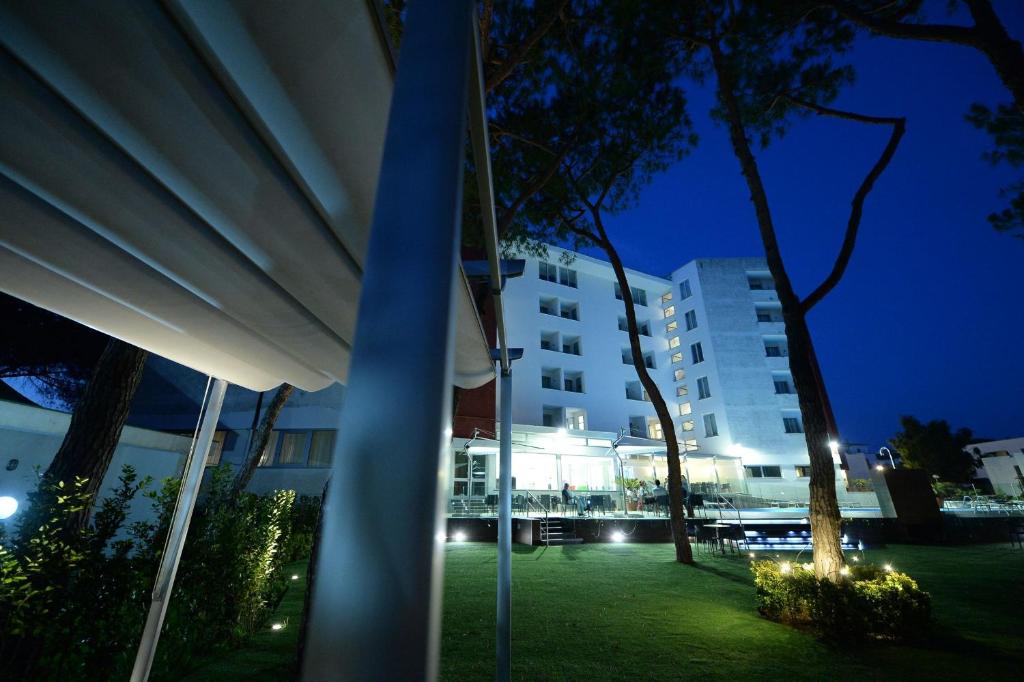 un grande edificio bianco di notte con alberi e luci di Giulivo Hotel & Village a Baia Domizia