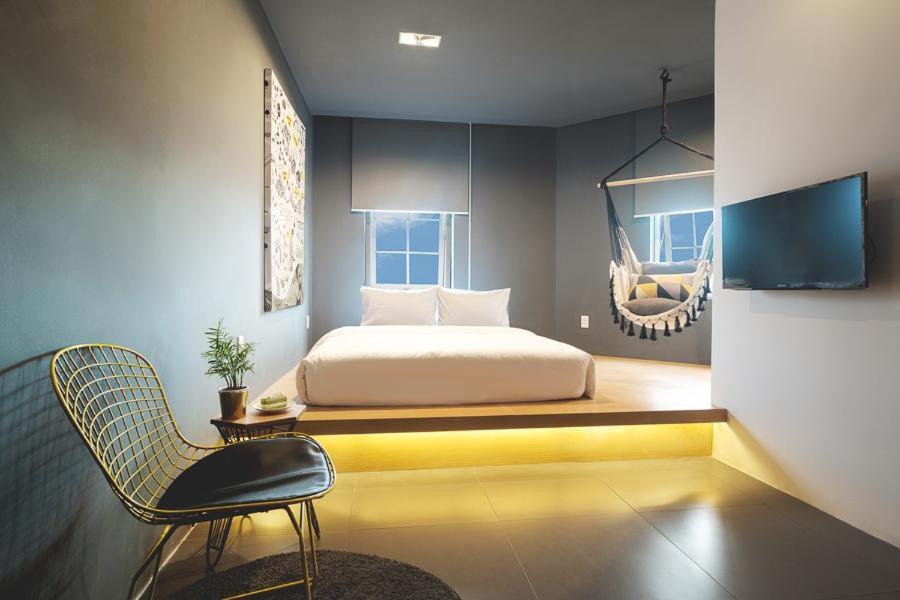 een slaapkamer met een bed en een stoel bij The Hammock Hotel Ben Thanh in Ho Chi Minh-stad