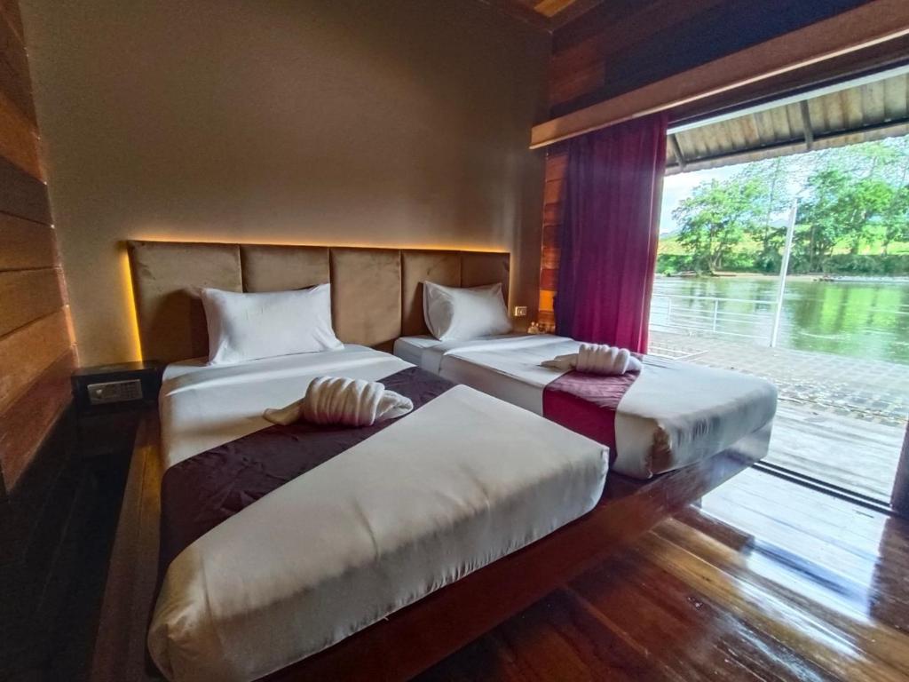 twee bedden in een kamer met een raam bij SAIYOK MANTRA RESORT : ไทรโยค มันตรา รีสอร์ท in Ban Huai Maenam Noi