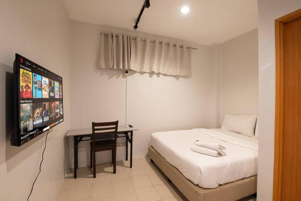 - une chambre avec un lit, une télévision et une chaise dans l'établissement JP Santiago Studio Makati J304, à Manille