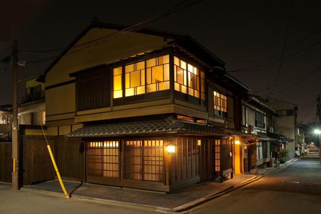 a building with lit windows on a street at night at Zen Machiya Private Residence near Heian Shrine in Kyoto