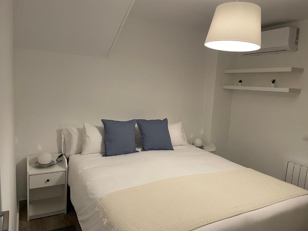 um quarto com uma cama branca e almofadas azuis em C1 Madrid, Zona exclusiva em Madri