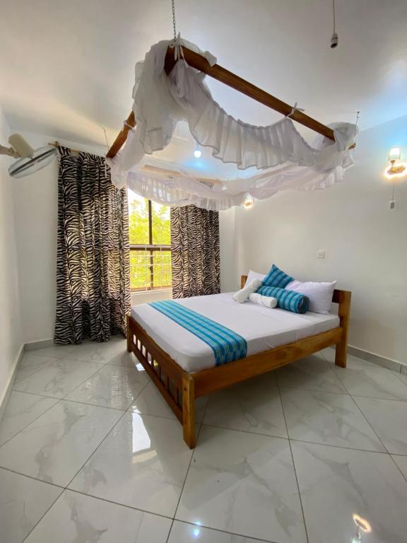 1 dormitorio con cama con dosel y ventana en Silent Palms Villa, en Galu