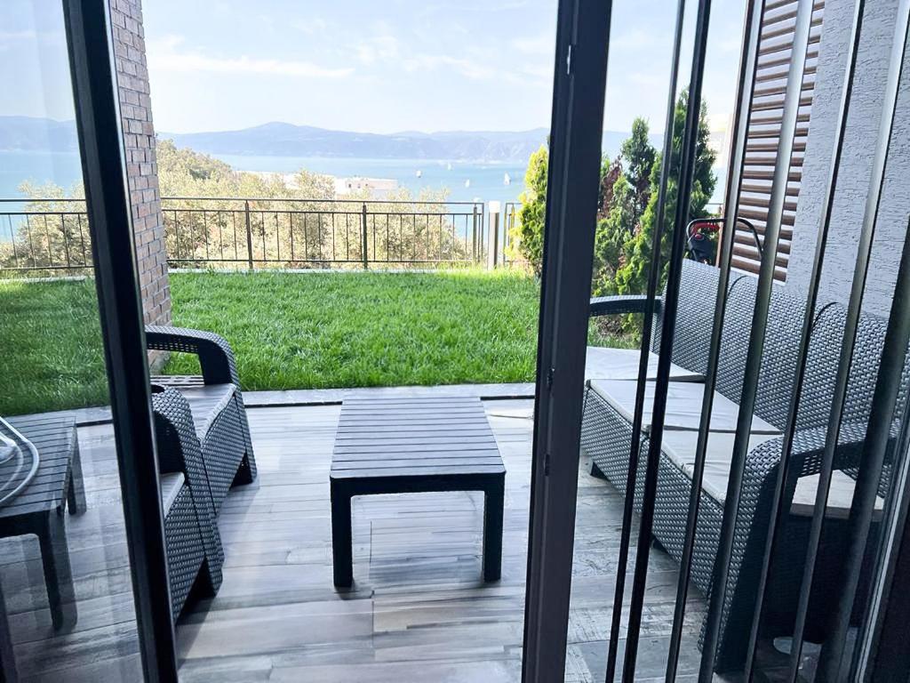 uma varanda com um banco, uma mesa e uma vista em Luxury Apartment with Garden right by sea em Mudanya