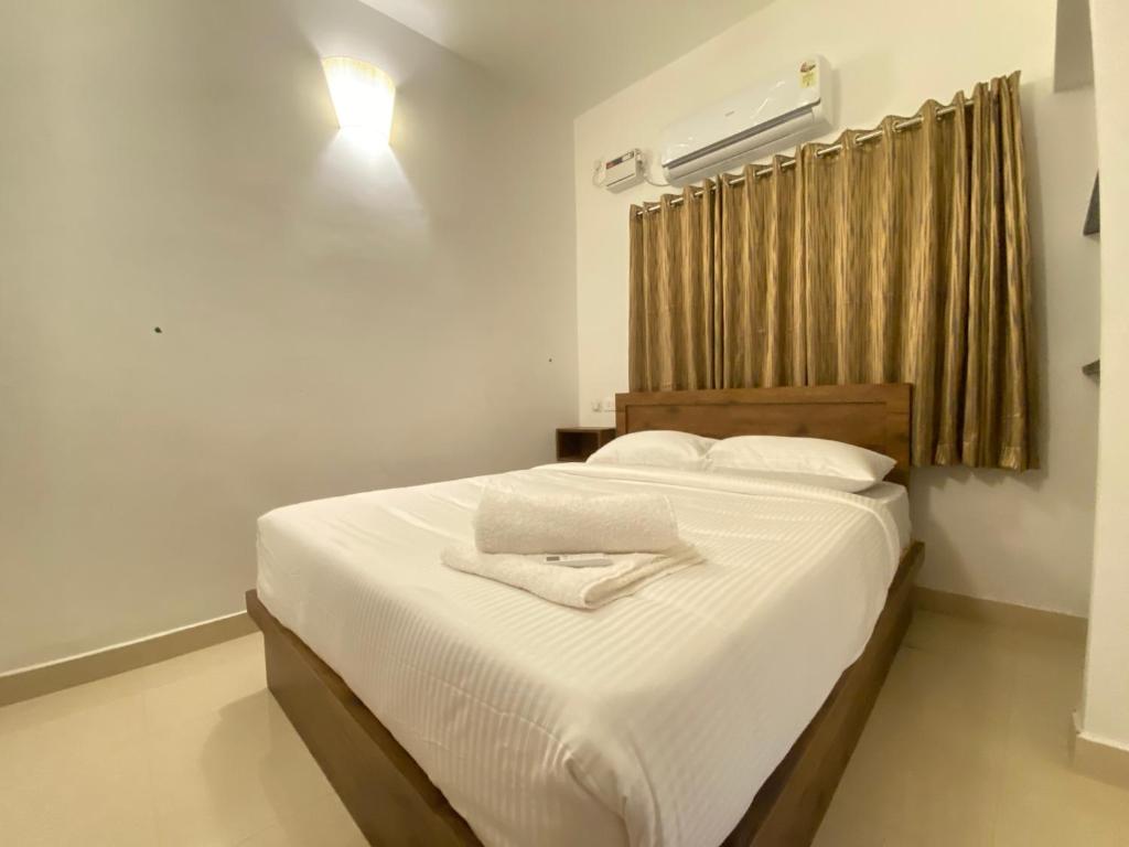 1 dormitorio con 1 cama con sábanas blancas y ventana en Le Poshe Suite en Pondicherry