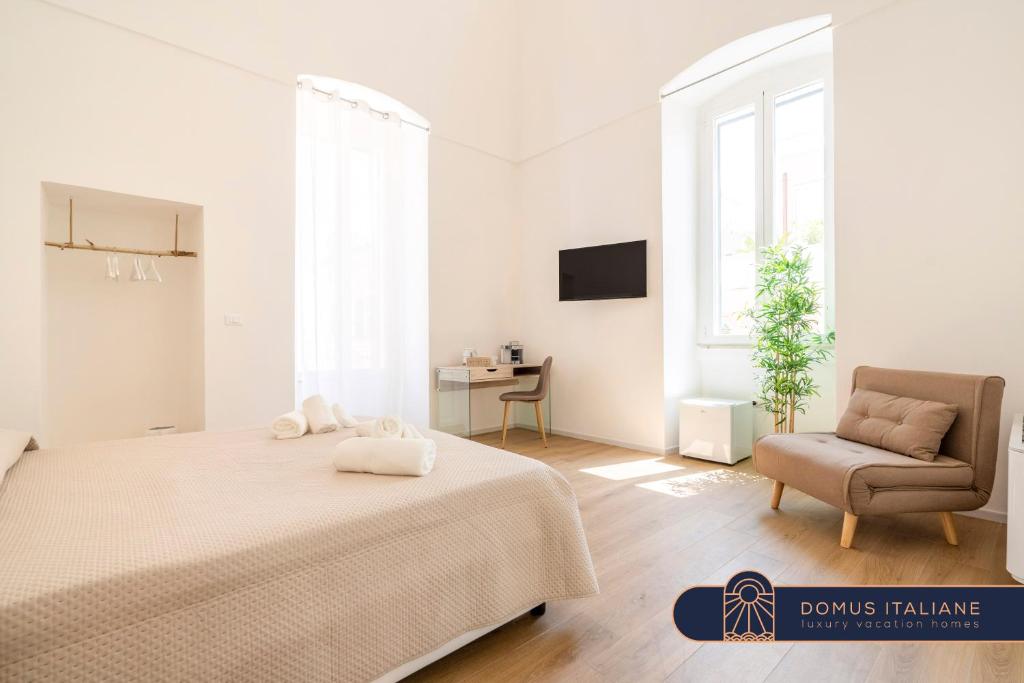 ein weißes Schlafzimmer mit einem Bett und einem Stuhl in der Unterkunft Casa Del Barone - Luxury Suites in Monopoli