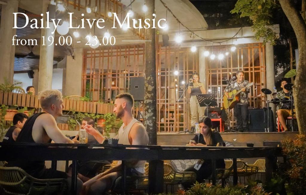 a group of people sitting at a table with a band at Grandmas Plus Hotel Seminyak in Seminyak