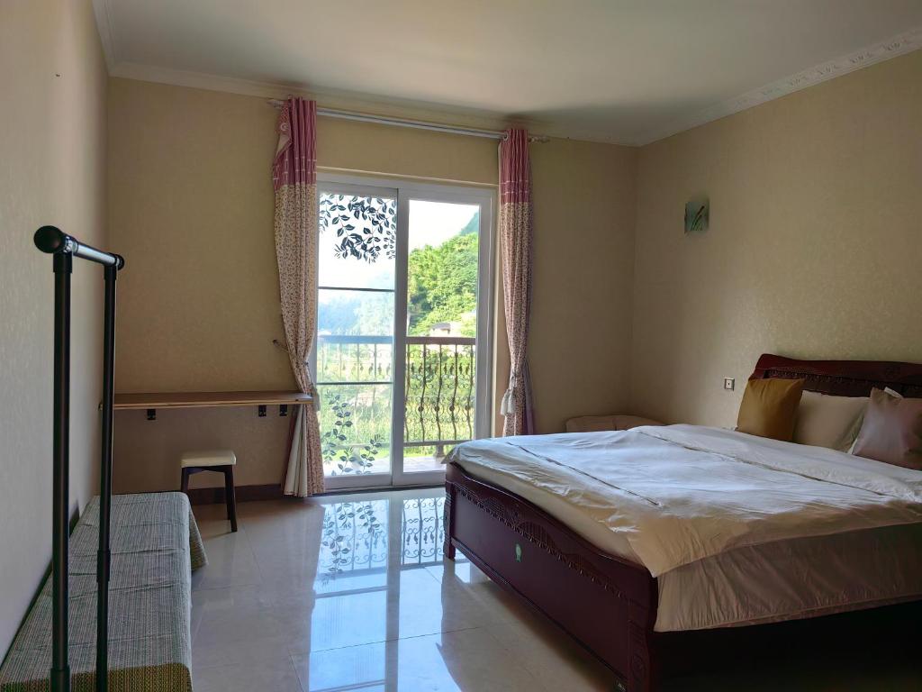 een slaapkamer met een bed en een groot raam bij Valley Oasis Villa in Enshi