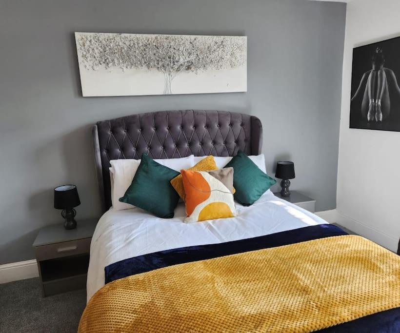 a bedroom with a large bed with colorful pillows at A Stunning 3Bed house with Wi-Fi and Parking in Chatham