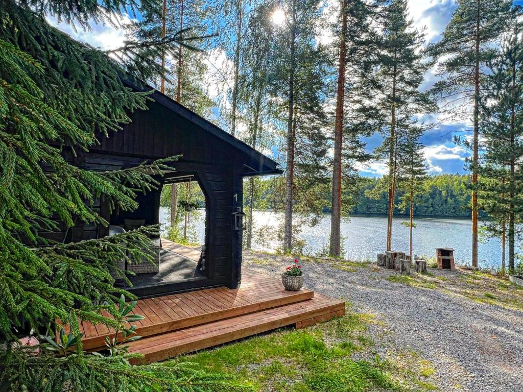 a cabin with a deck next to a body of water at Iken Mökit in Heinola