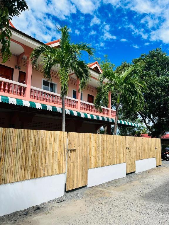 a fence in front of a house with palm trees at Casa Cactus in Bangrak Beach