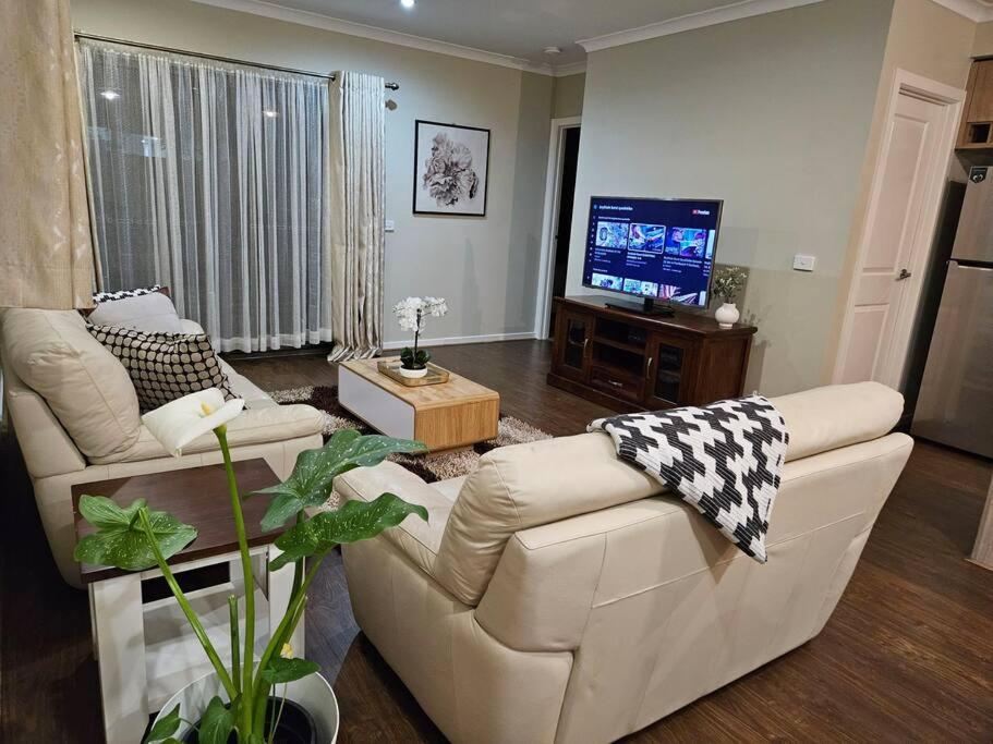 a living room with two white couches and a television at Tranquil home in Point Cook. in Point Cook