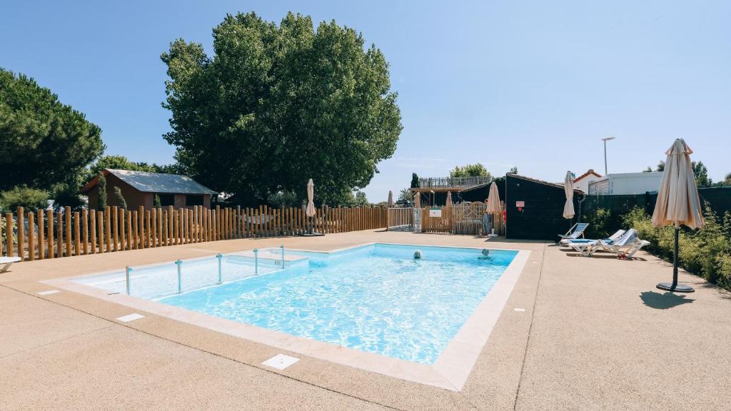 a swimming pool in a yard with a fence at Camping La Prée in Les Portes