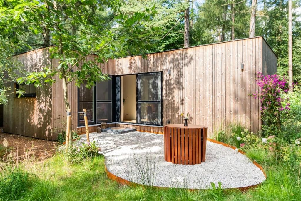 ein Haus mit einem hölzernen Baumstumpf in der Mitte eines Gartens in der Unterkunft Luxe-Avontuur in een Romantische Cabin in het Bos in Stekene