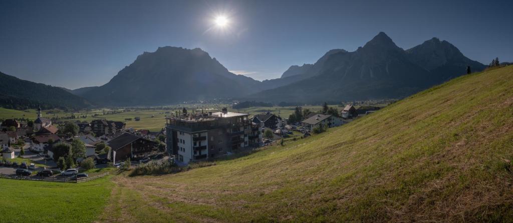 a village on a hill with mountains in the background at Boutique Hotel Bellevue Lermoos in Lermoos
