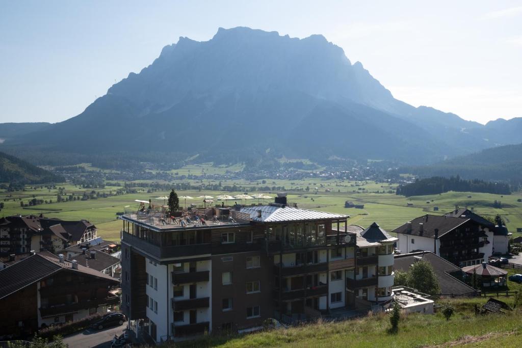 a building on a hill with a mountain in the background at Boutique Hotel Bellevue Lermoos in Lermoos