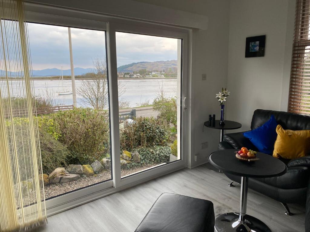 a living room with a large sliding glass door at Ards House Self catering apartment with sea views in Oban
